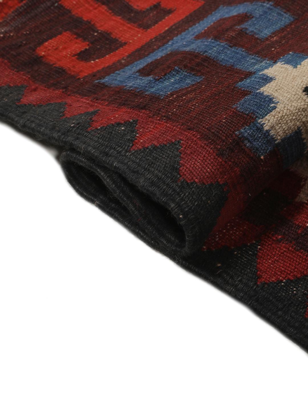 Tapis Kelim afghan tissé à la main avec des motifs géométriques en losange dans les tons rouge, bleu et noir.