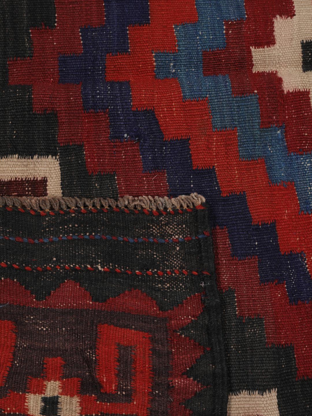 Tapis Kelim afghan tissé à la main avec des motifs géométriques en losange dans les tons rouge, bleu et noir.