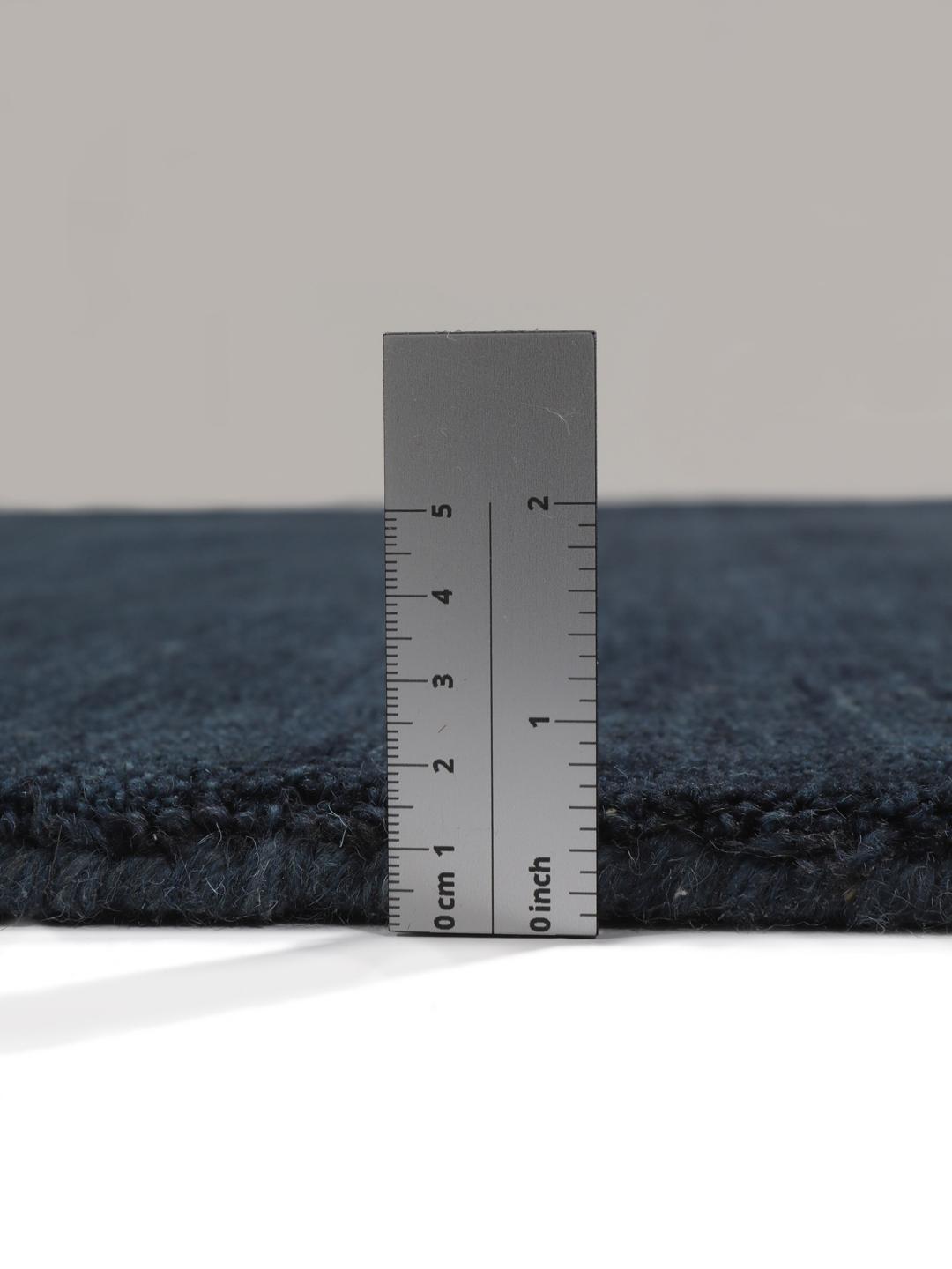 Et mørkeblåt håndvævet tæppe med kort luv og korte frynser langs kanterne