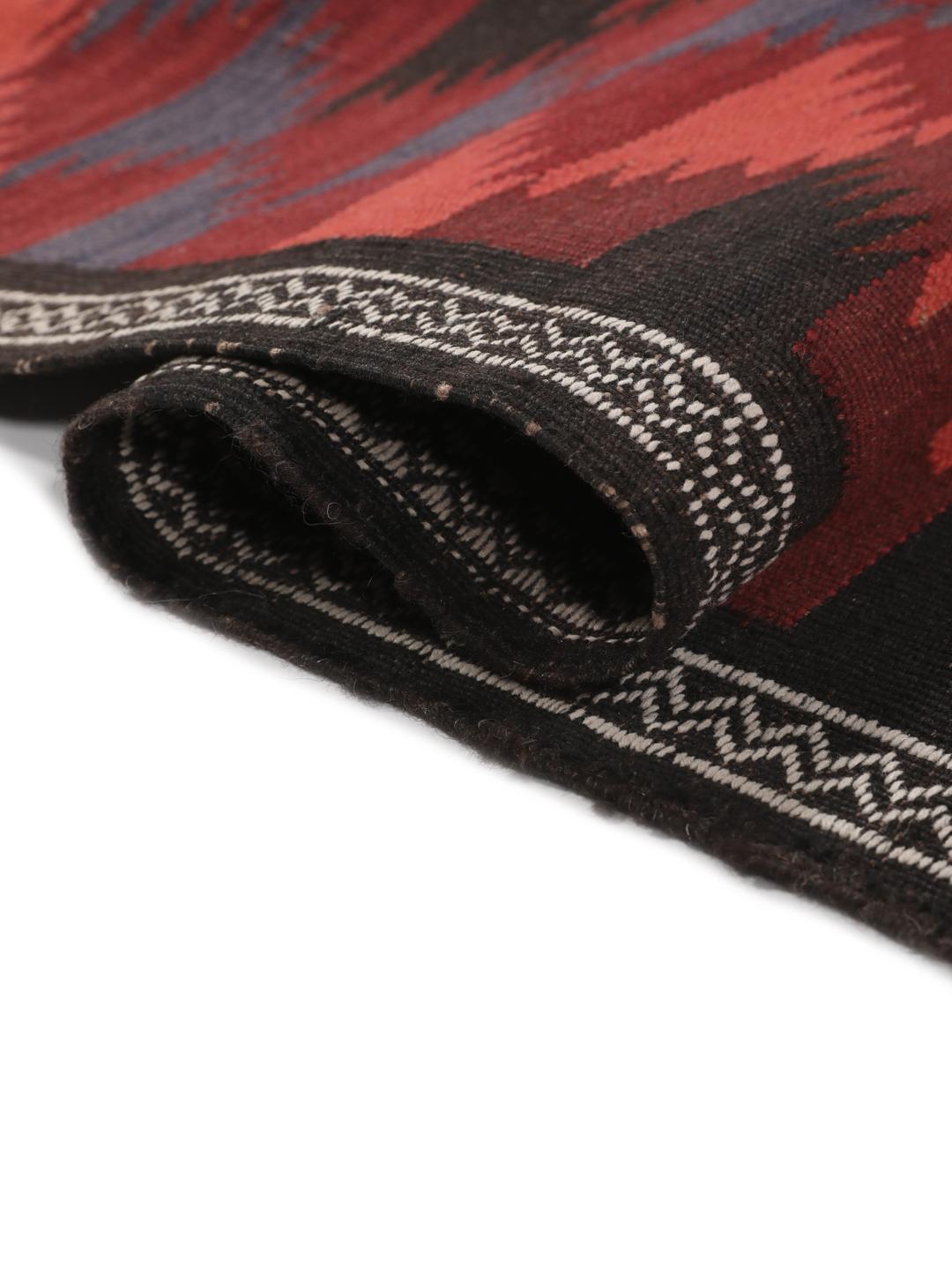 Tapis kelim afghan tissé à la main avec des motifs géométriques dans des tons rouges et sombres.
