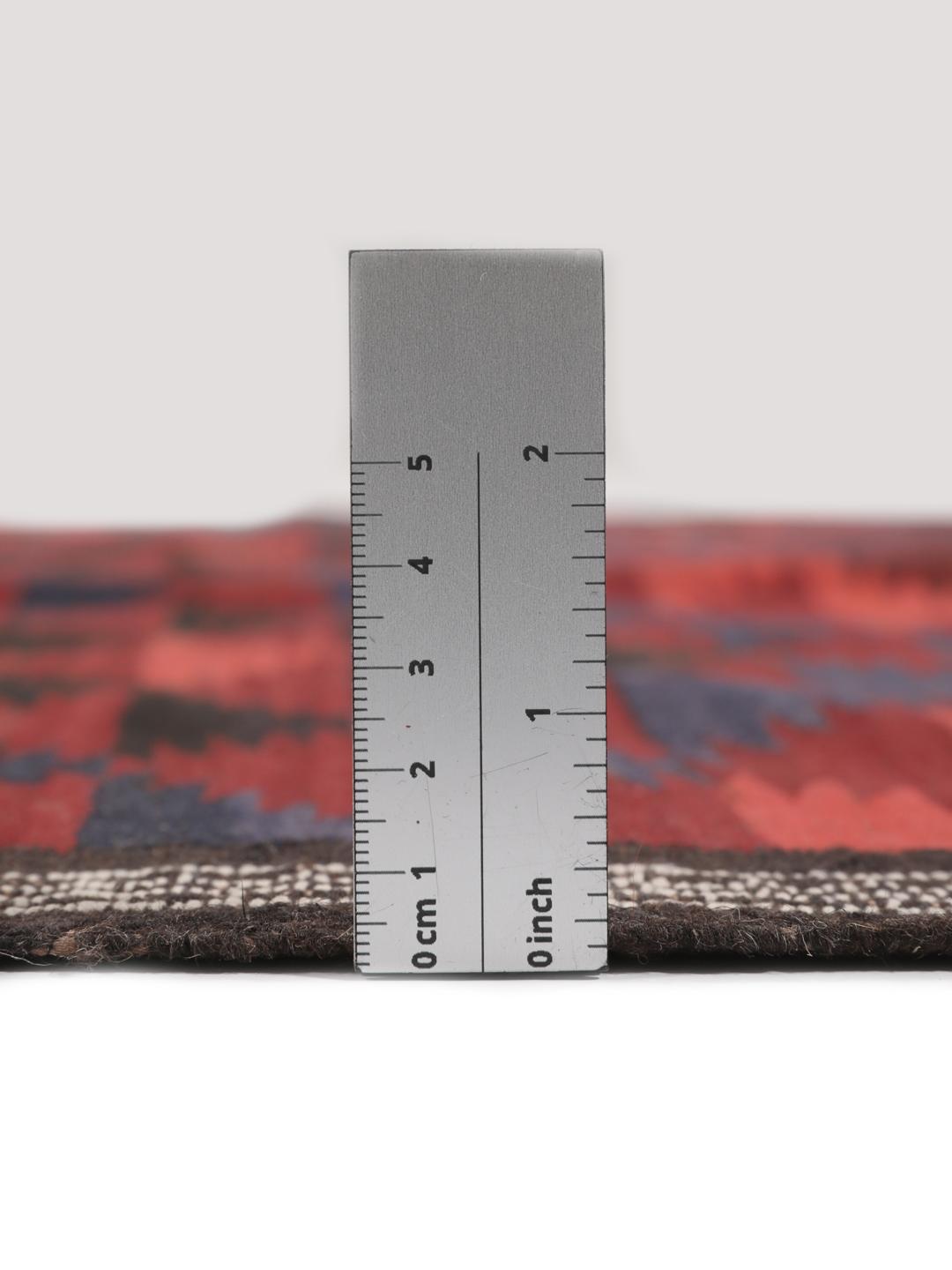 Tapis kelim afghan tissé à la main avec des motifs géométriques dans des tons rouges et sombres.
