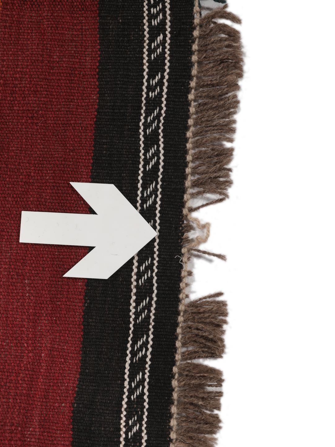 Tapis kelim afghan tissé à la main avec des motifs géométriques dans des tons rouges et sombres.