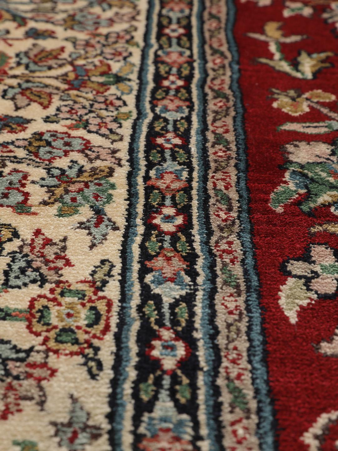 Et håndknyttet Kashmir silketæppe fra Indien med et rødt felt og et indviklet blomstermedaljonmønster.