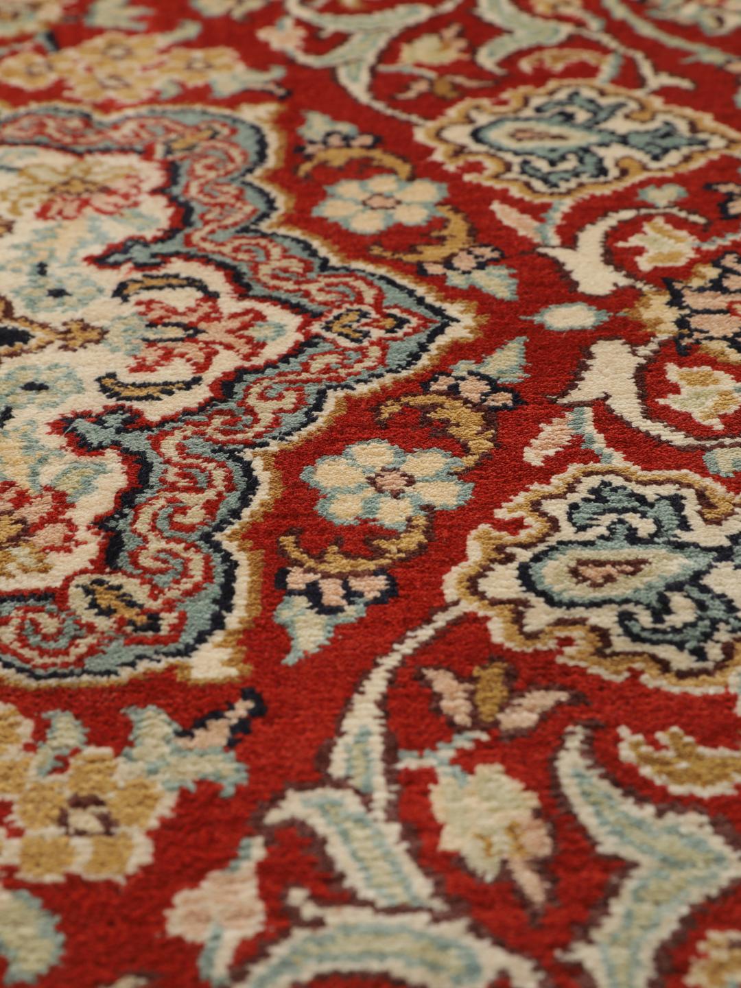 Hand-knotted Kashmir silk rug from India with a vibrant red field and intricate floral motifs.