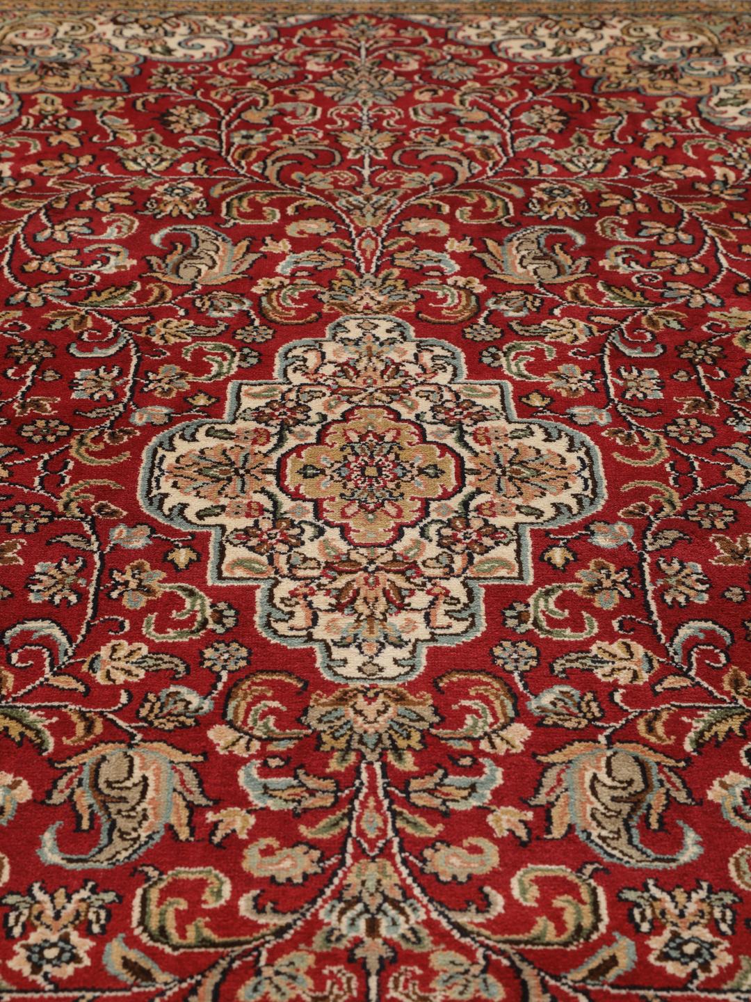 Een handgeknoopt Kashmir zijden tapijt uit India met een levendig rood veld en bloemmotieven.