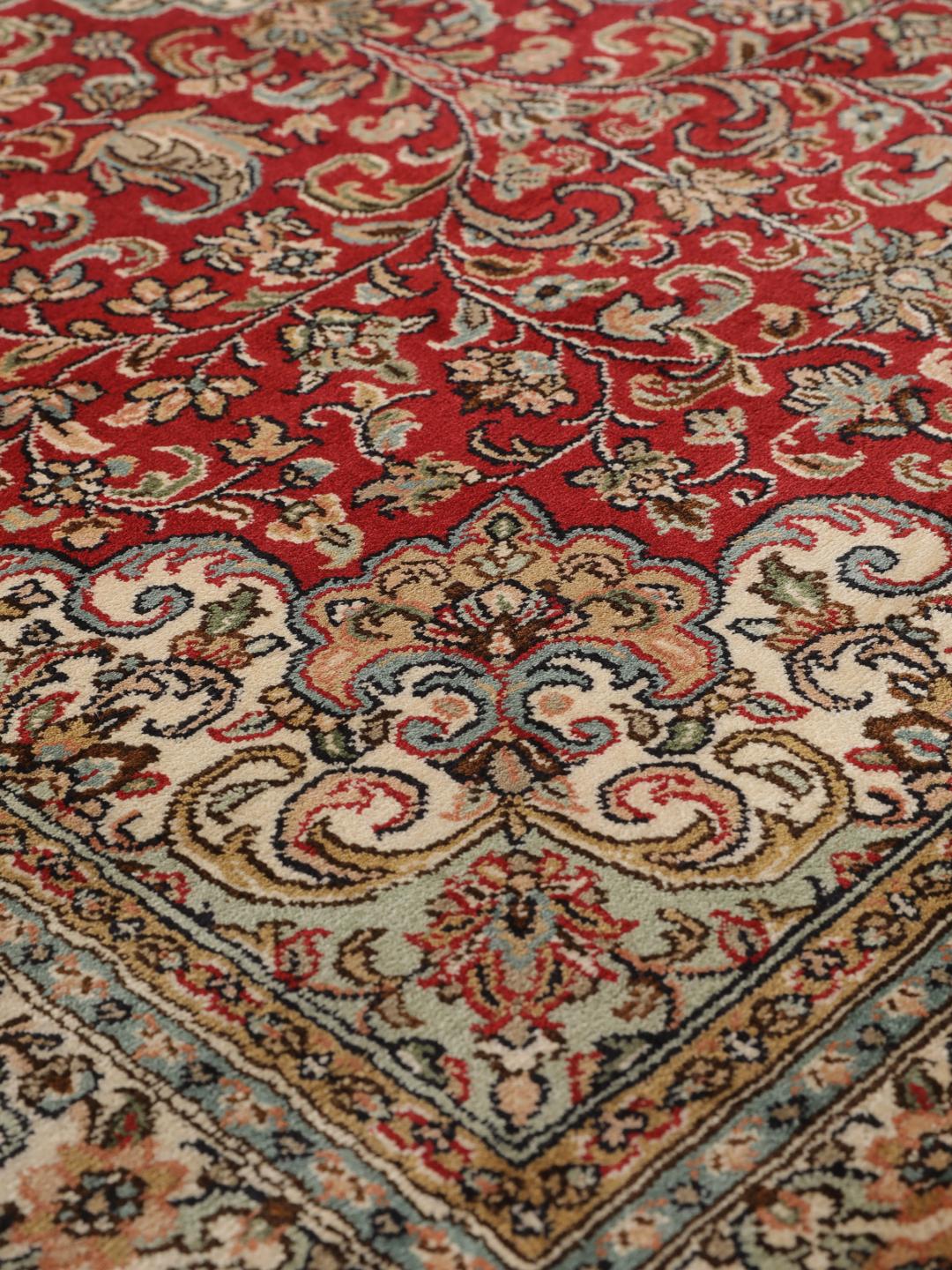 Een handgeknoopt Kashmir zijden tapijt uit India met een levendig rood veld en bloemmotieven.