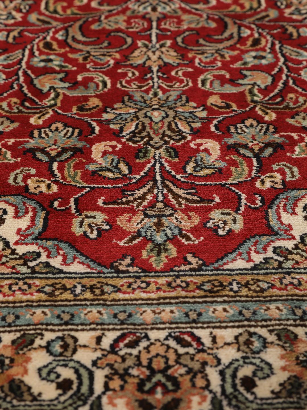Een handgeknoopt Kashmir zijden tapijt uit India met een levendig rood veld en bloemmotieven.