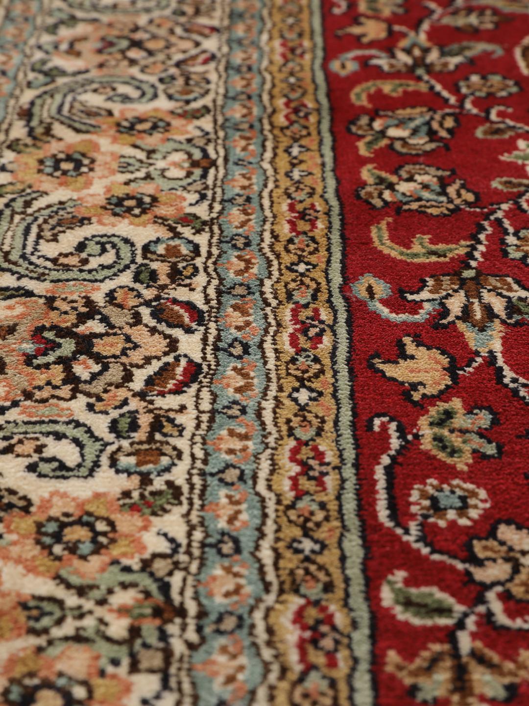 Een handgeknoopt Kashmir zijden tapijt uit India met een levendig rood veld en bloemmotieven.