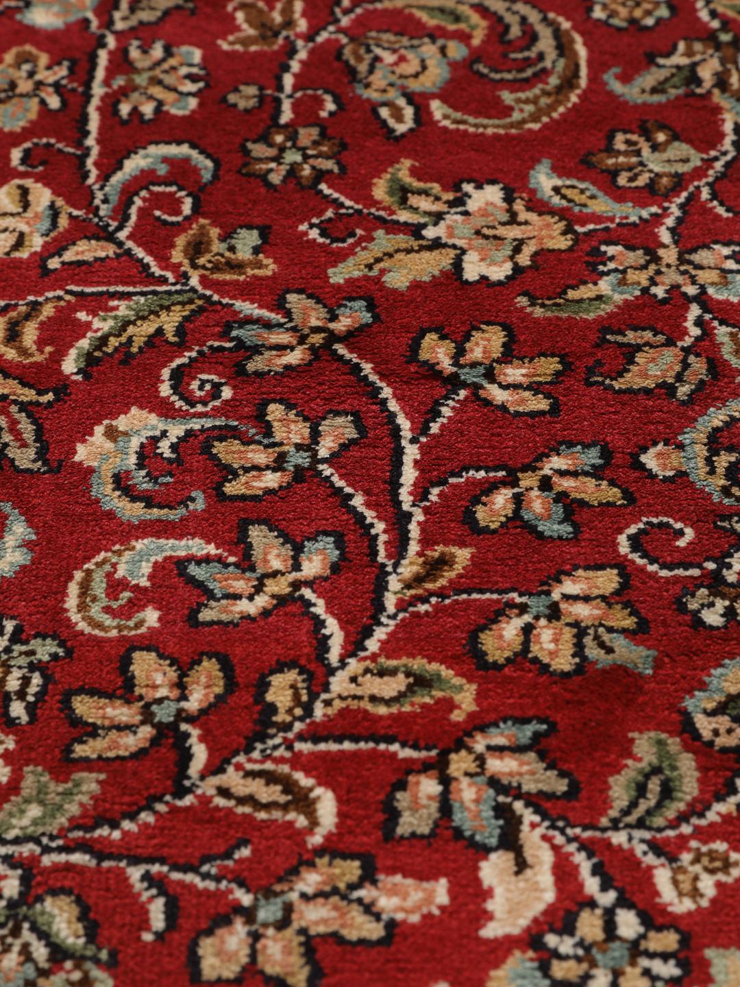 Een handgeknoopt Kashmir zijden tapijt uit India met een levendig rood veld en bloemmotieven.