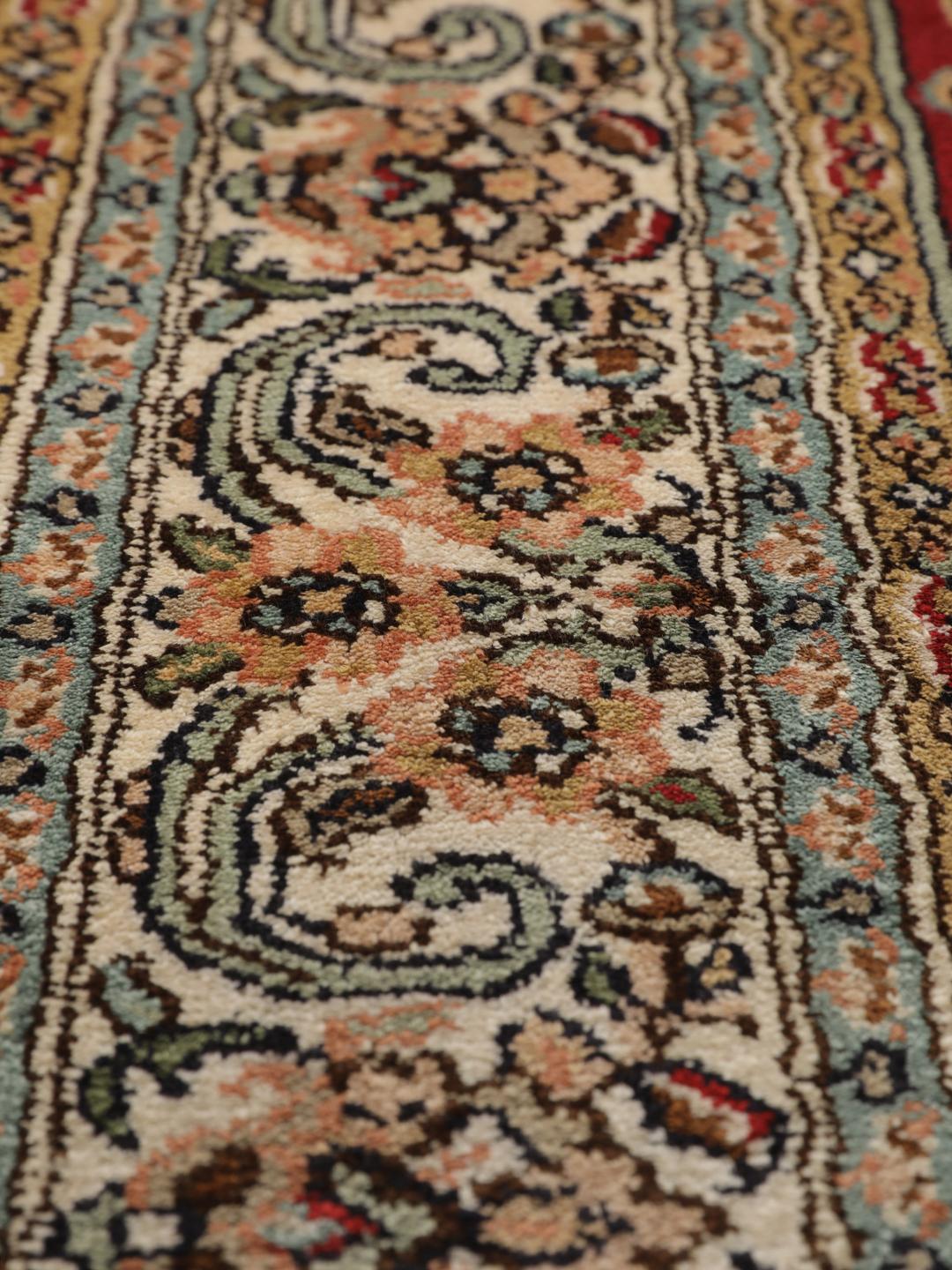 Een handgeknoopt Kashmir zijden tapijt uit India met een levendig rood veld en bloemmotieven.