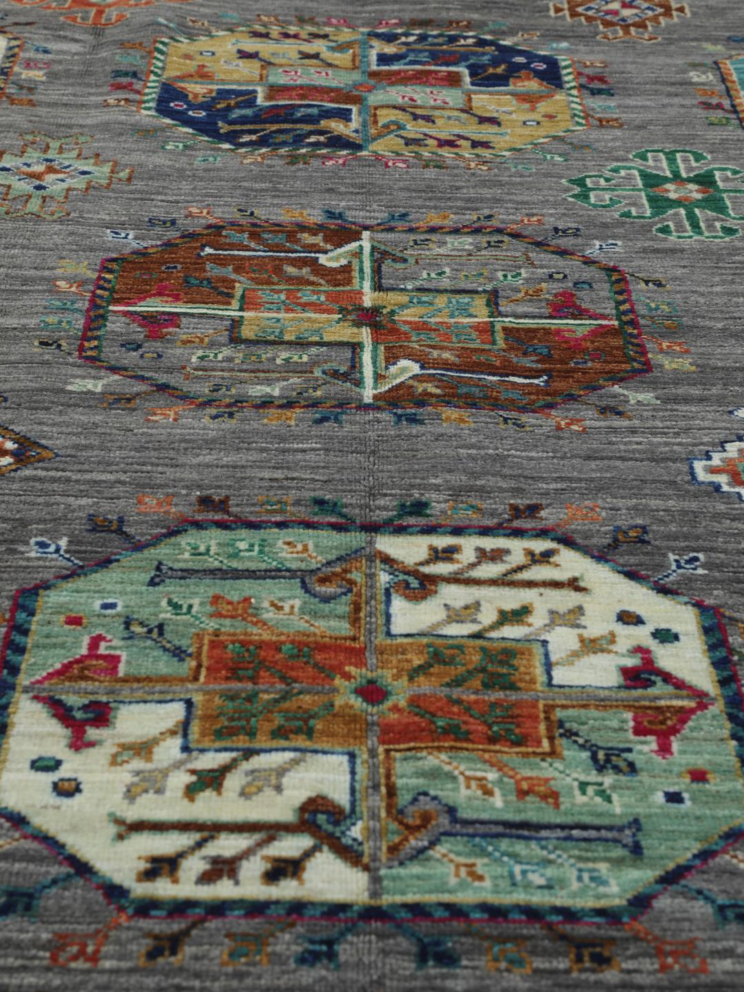 Hand-knotted rug from the Middle East with vibrant geometric medallions on a grey background