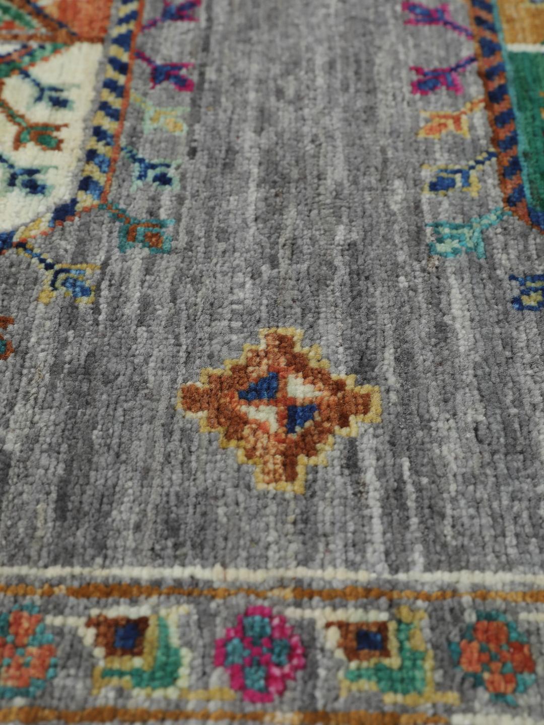 Hand-knotted rug from the Middle East with vibrant geometric medallions on a grey background