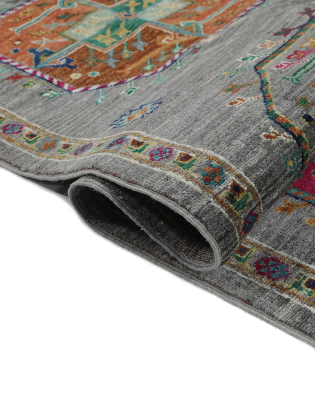 Hand-knotted rug from the Middle East with vibrant geometric medallions on a grey background