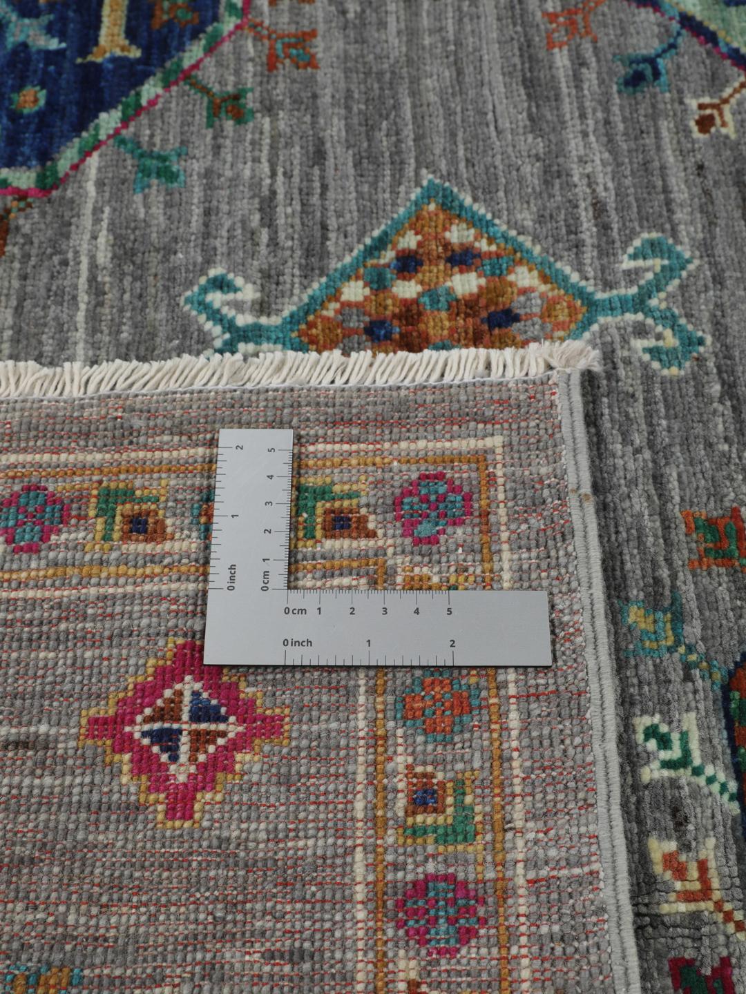 Hand-knotted rug from the Middle East with vibrant geometric medallions on a grey background