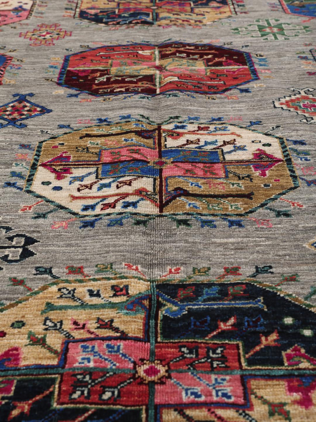 Hand-knotted Afghan rug with vibrant medallion patterns on a grey field