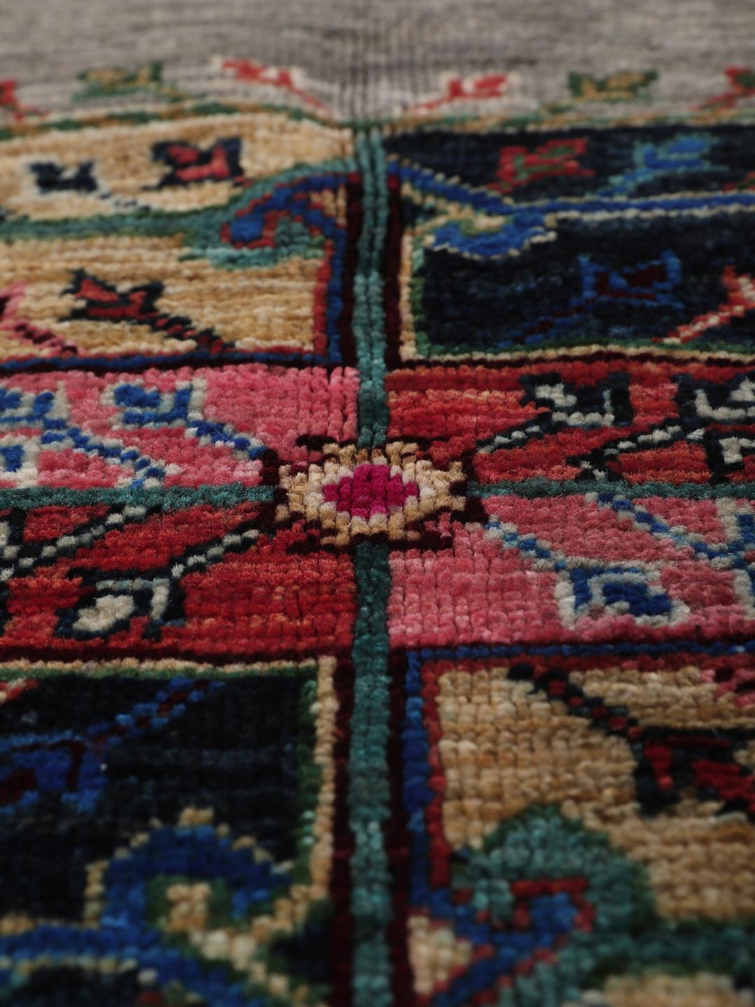 Hand-knotted Afghan rug with vibrant medallion patterns on a grey field