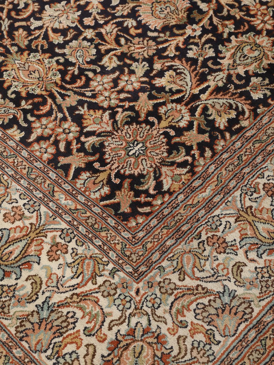 Et håndknyttet sort Kashmir-silketæppe med indviklede blomstermotiver og en dekorativ kant.