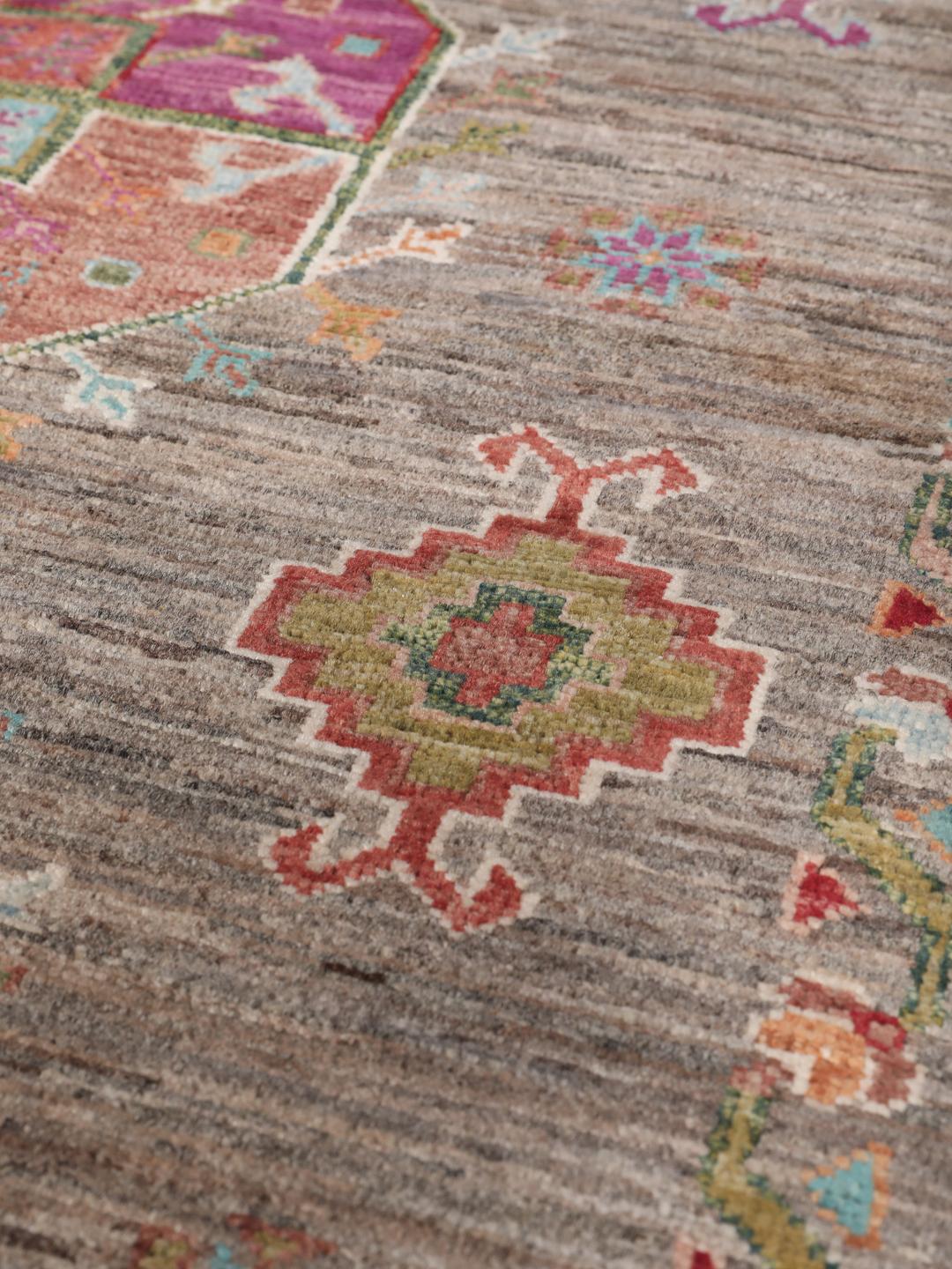 A unique Afghan wool runner featuring colourful geometric motifs on a grey background