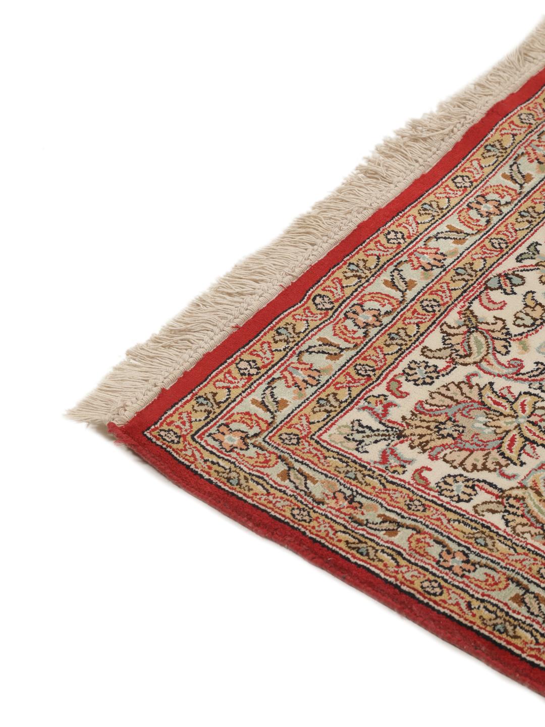 Et håndknyttet Kashmir-silketæppe fra Indien med et indviklet blomstermedallion-mønster i røde og beige nuancer.