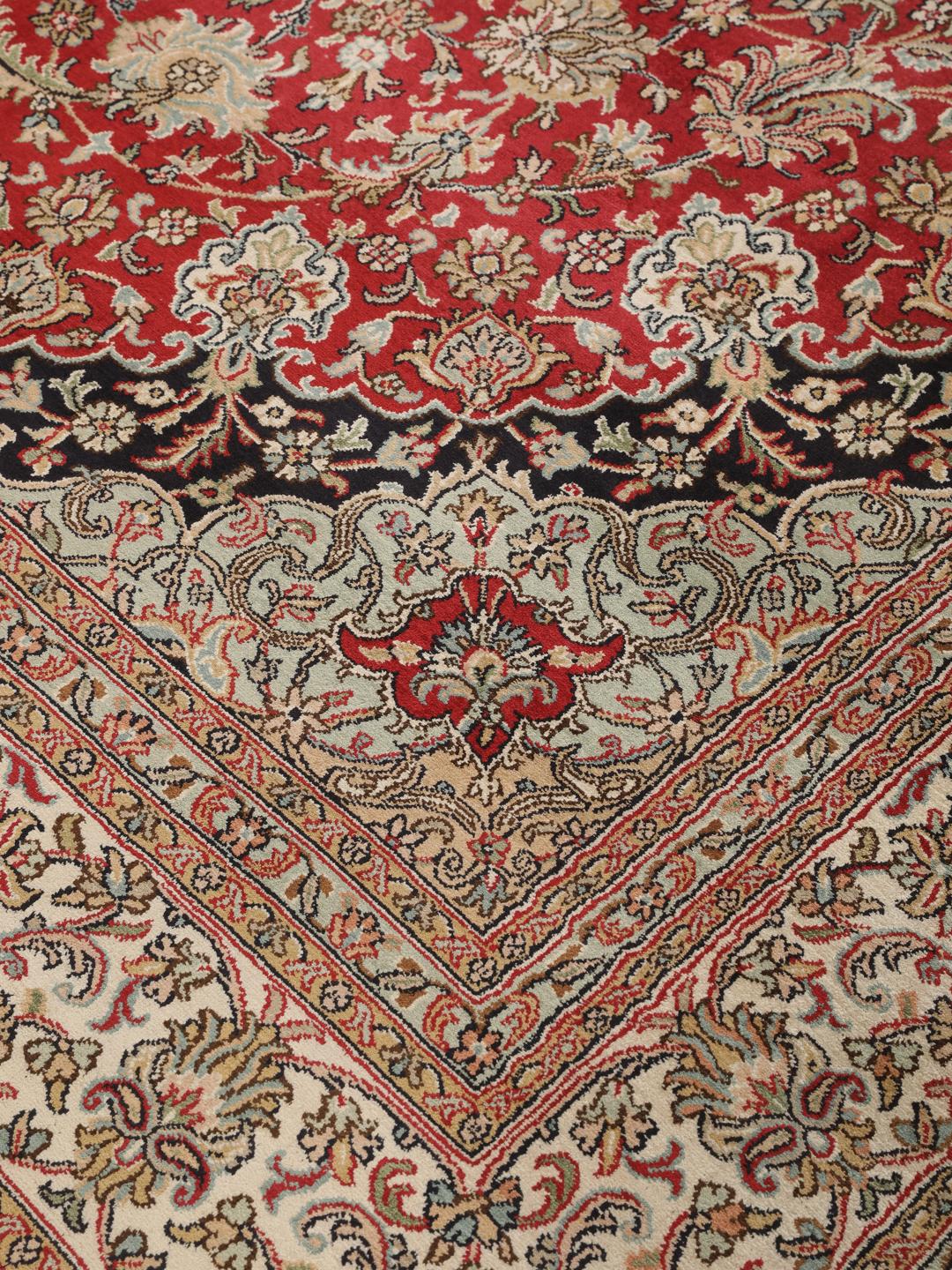 Et håndknyttet Kashmir-silketæppe fra Indien med et indviklet blomstermedallion-mønster i røde og beige nuancer.