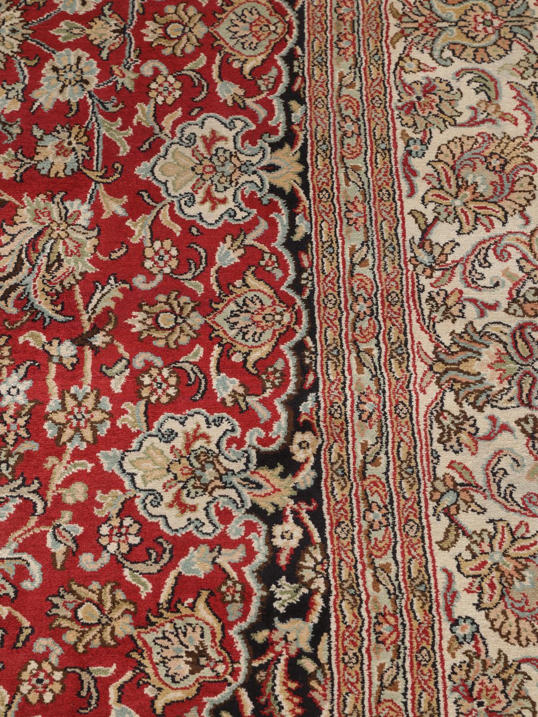 Et håndknyttet Kashmir-silketæppe fra Indien med et indviklet blomstermedallion-mønster i røde og beige nuancer.