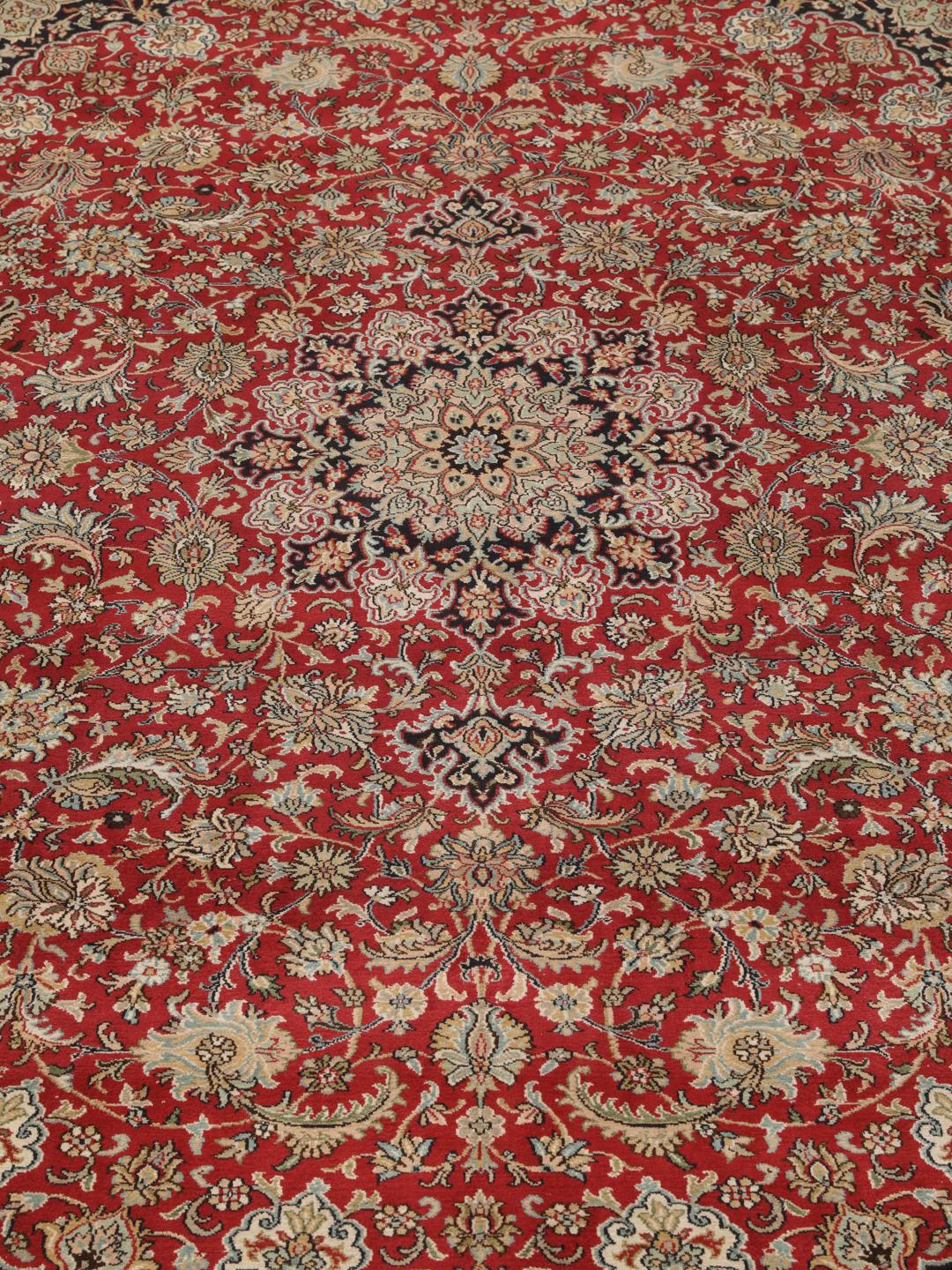 Et håndknyttet Kashmir-silketæppe fra Indien med et indviklet blomstermedallion-mønster i røde og beige nuancer.