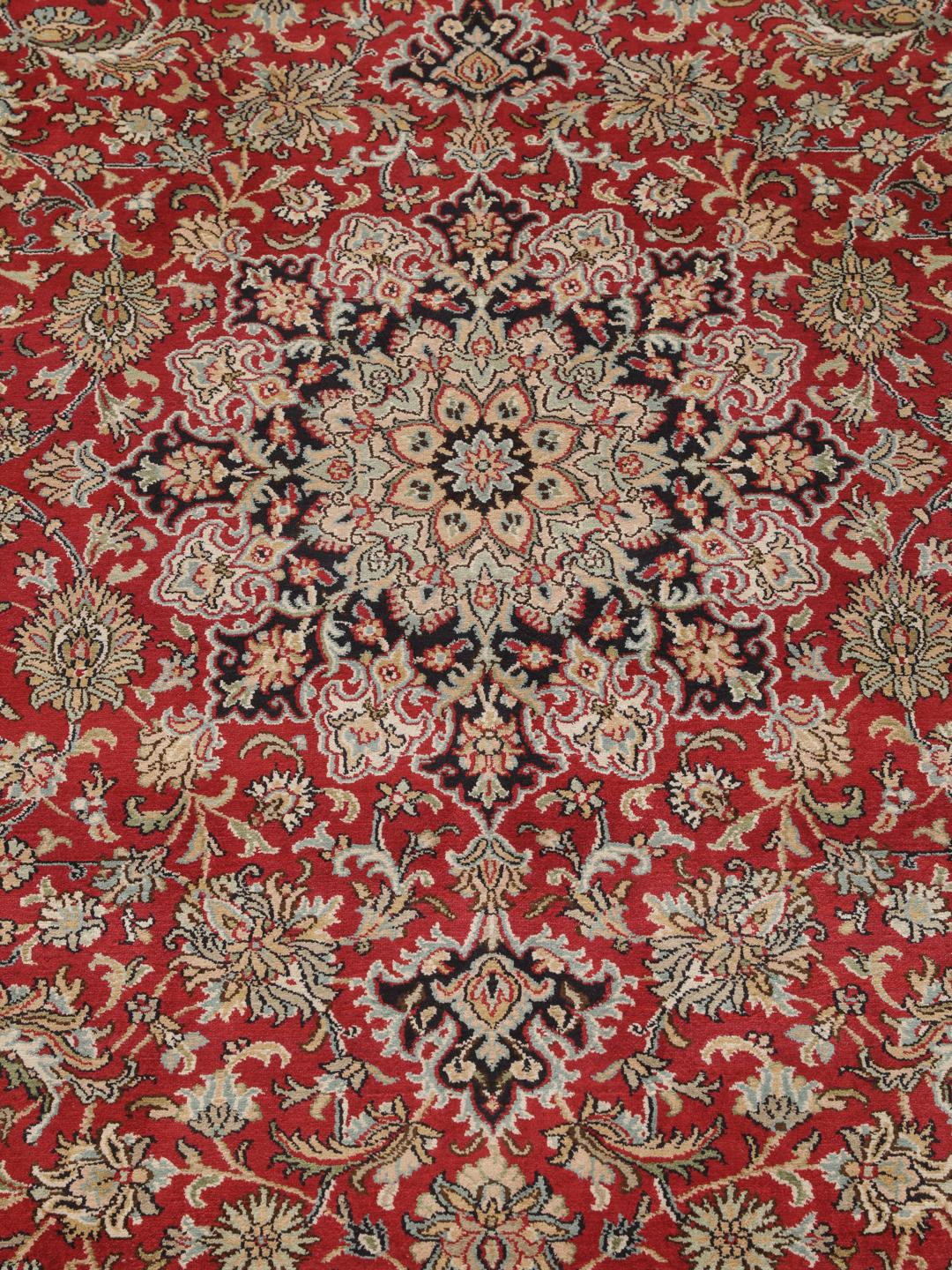 Et håndknyttet Kashmir-silketæppe fra Indien med et indviklet blomstermedallion-mønster i røde og beige nuancer.