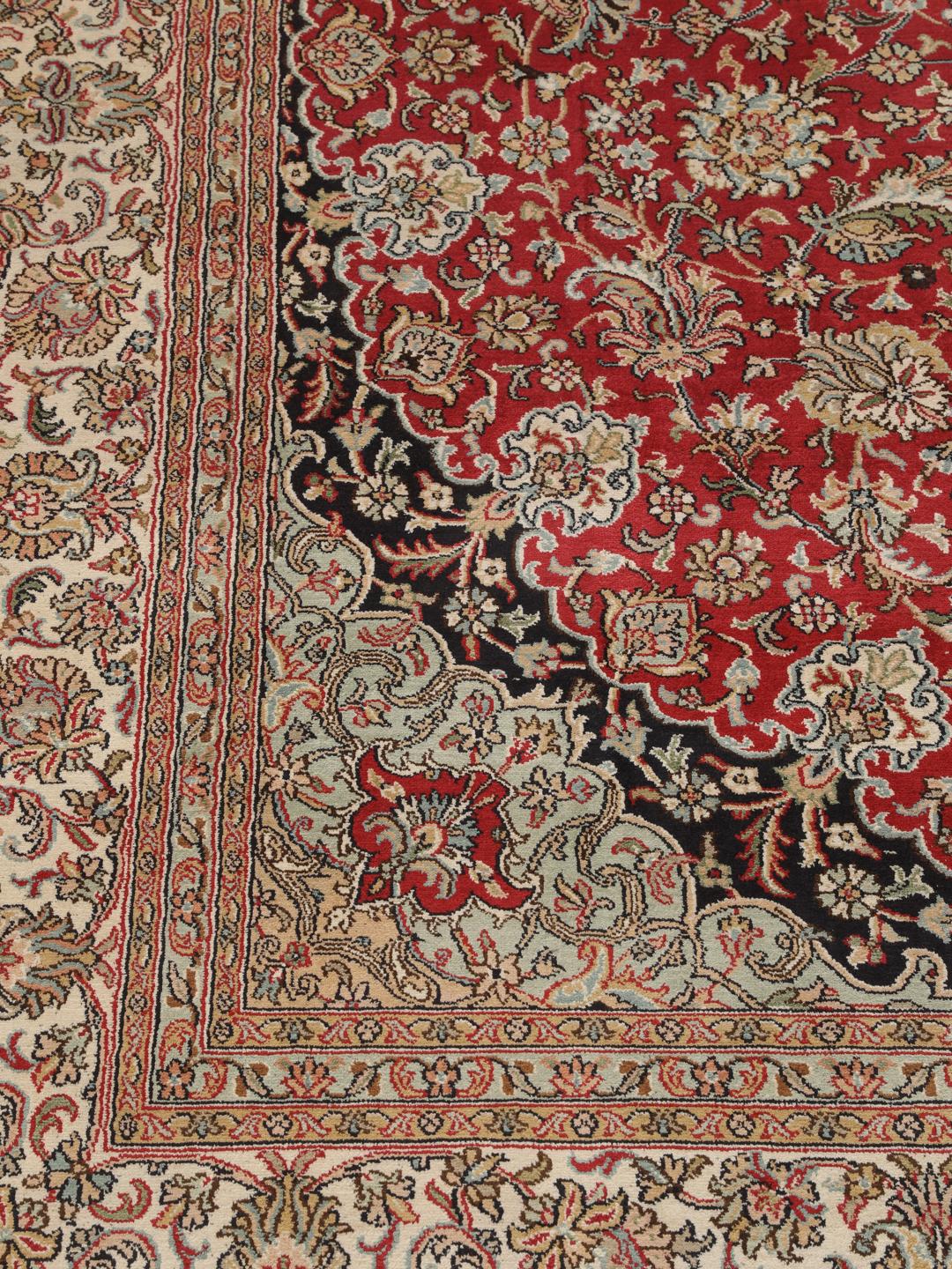 Et håndknyttet Kashmir-silketæppe fra Indien med et indviklet blomstermedallion-mønster i røde og beige nuancer.