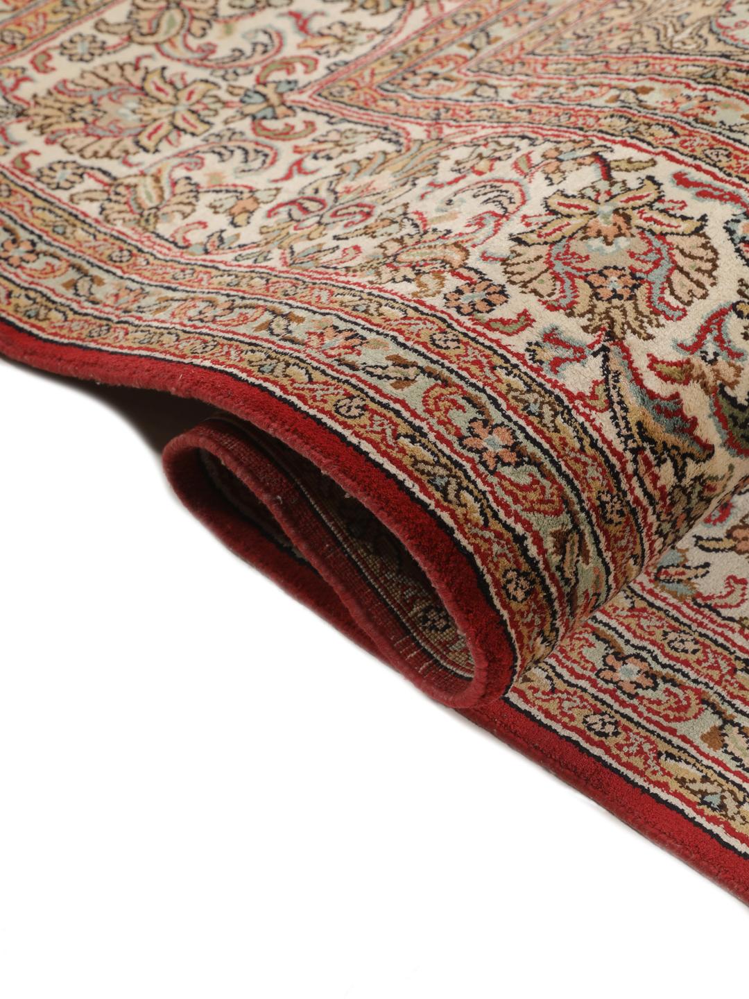Et håndknyttet Kashmir-silketæppe fra Indien med et indviklet blomstermedallion-mønster i røde og beige nuancer.