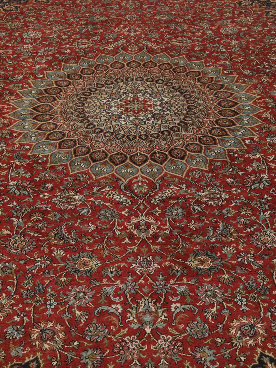 A large rectangular Kashmir silk rug from India with a central medallion on a red field.