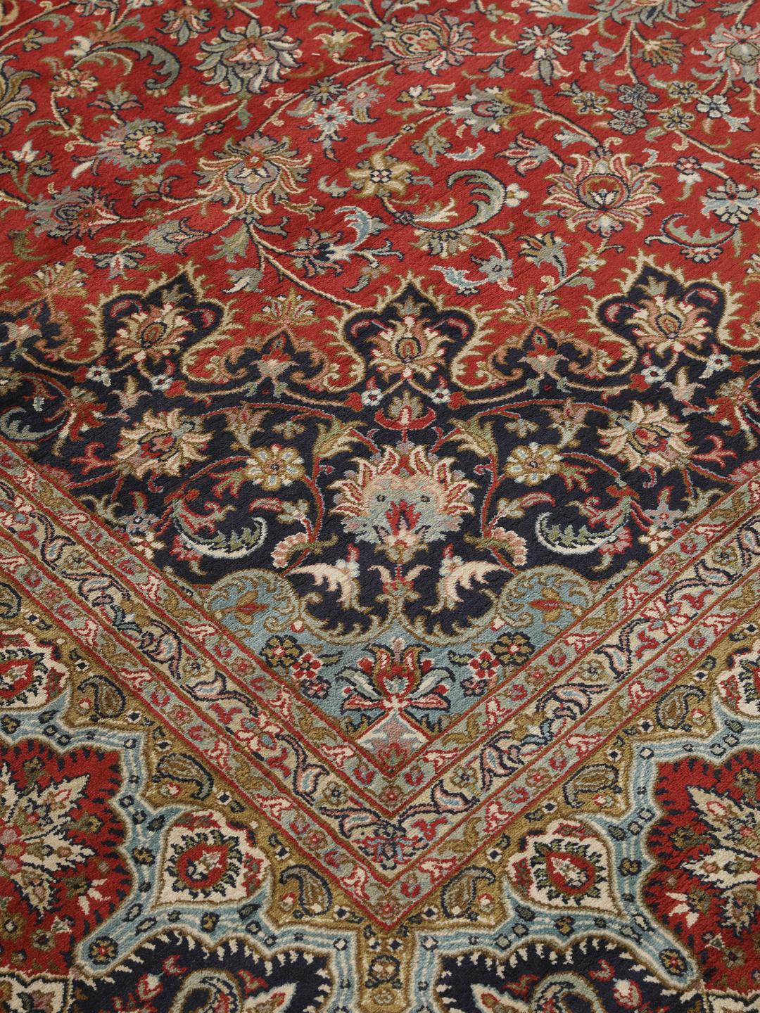 A large rectangular Kashmir silk rug from India with a central medallion on a red field.