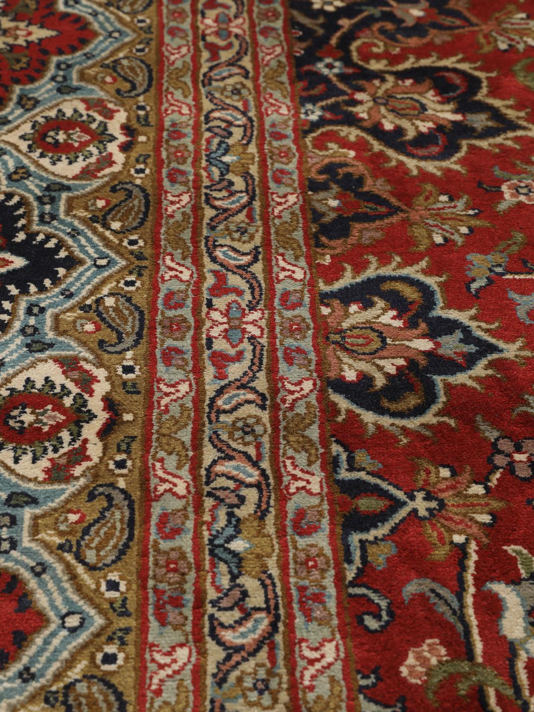 A large rectangular Kashmir silk rug from India with a central medallion on a red field.