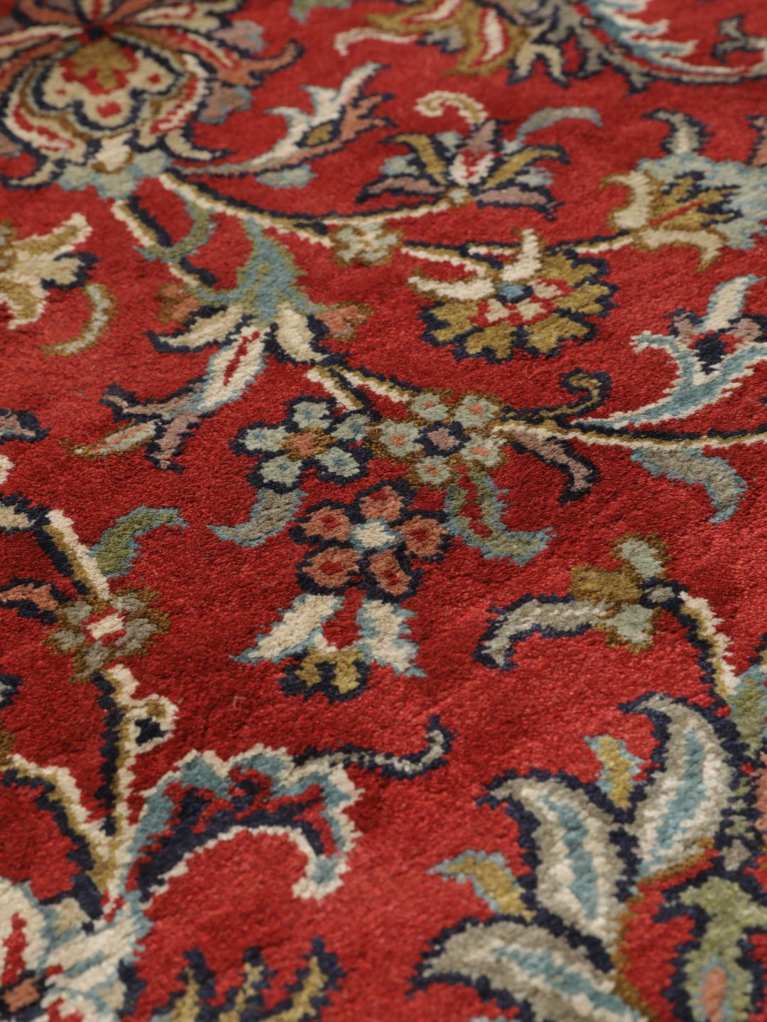 A large rectangular Kashmir silk rug from India with a central medallion on a red field.