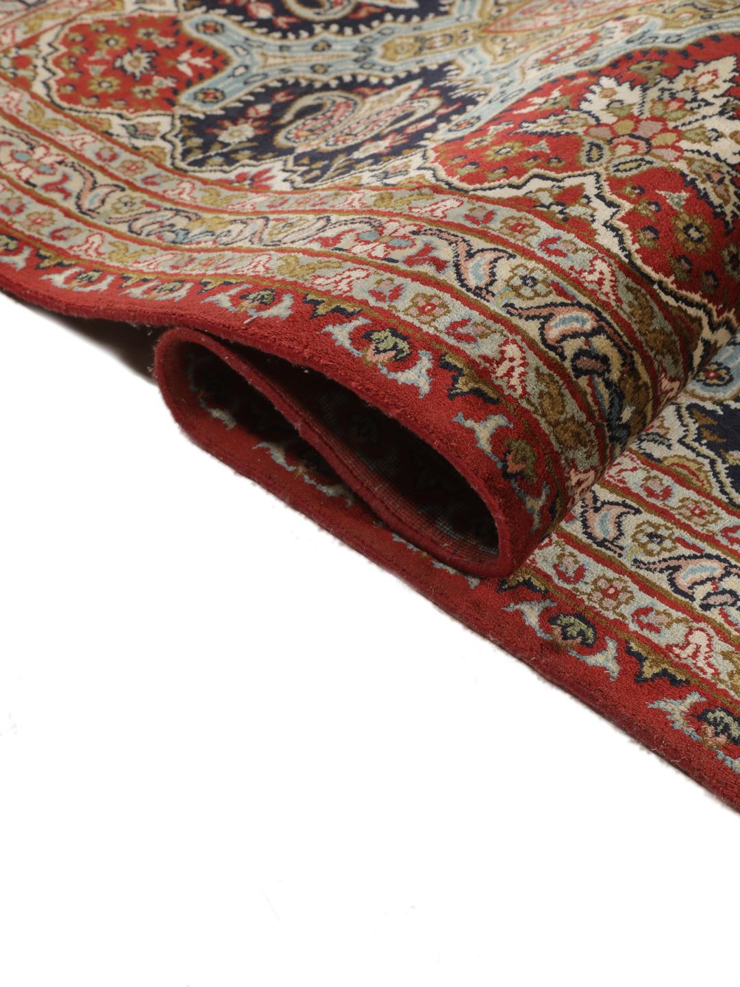 A large rectangular Kashmir silk rug from India with a central medallion on a red field.