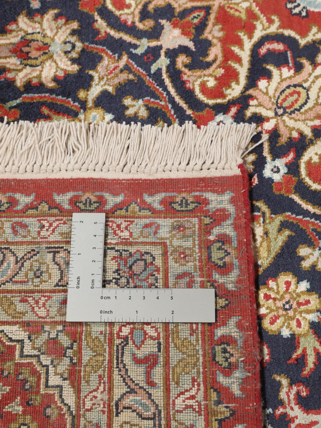 A large rectangular Kashmir silk rug from India with a central medallion on a red field.