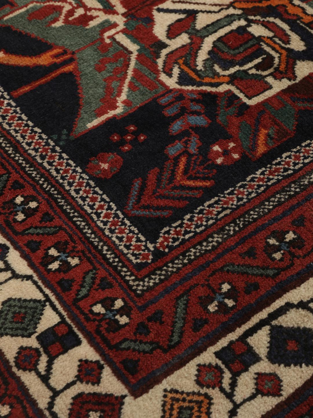 Hand-knotted Afshar wool rug from the Middle East featuring a dark-red and black floral design.