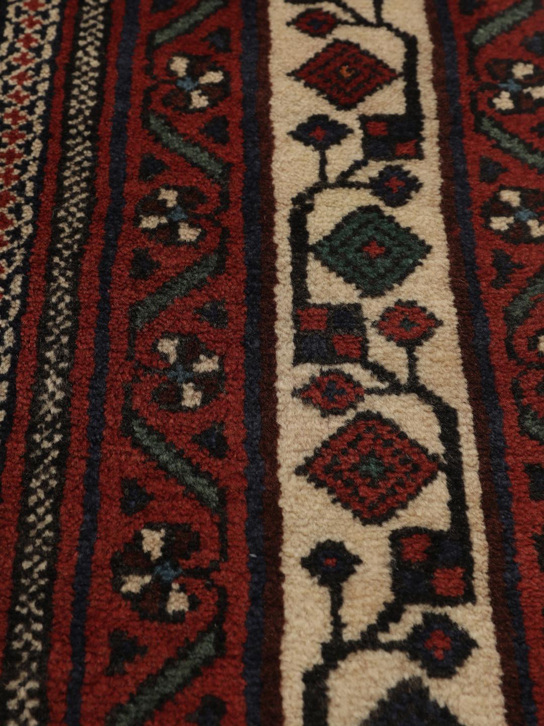 Hand-knotted Afshar wool rug from the Middle East featuring a dark-red and black floral design.