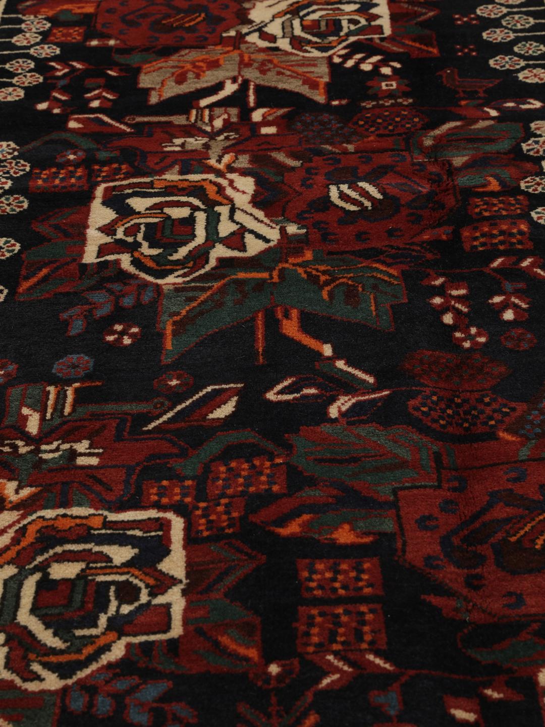 Hand-knotted Afshar wool rug from the Middle East featuring a dark-red and black floral design.