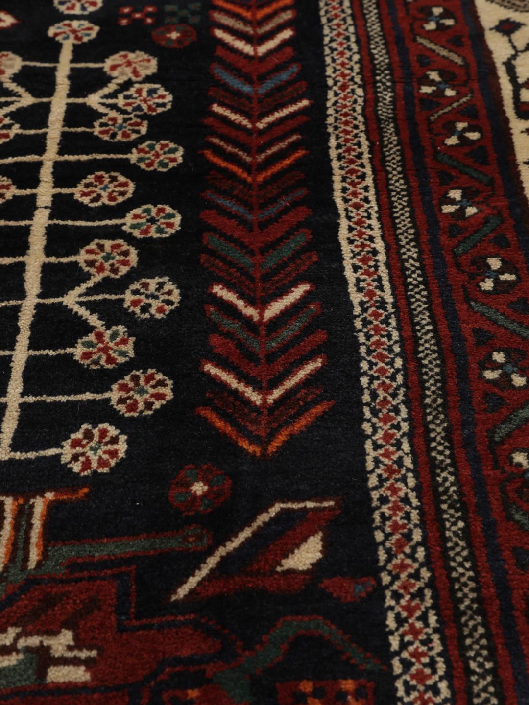 Hand-knotted Afshar wool rug from the Middle East featuring a dark-red and black floral design.