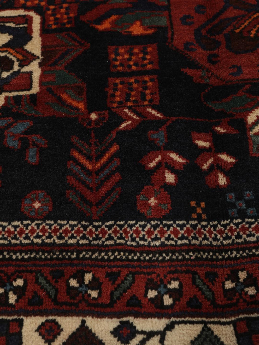 Hand-knotted Afshar wool rug from the Middle East featuring a dark-red and black floral design.