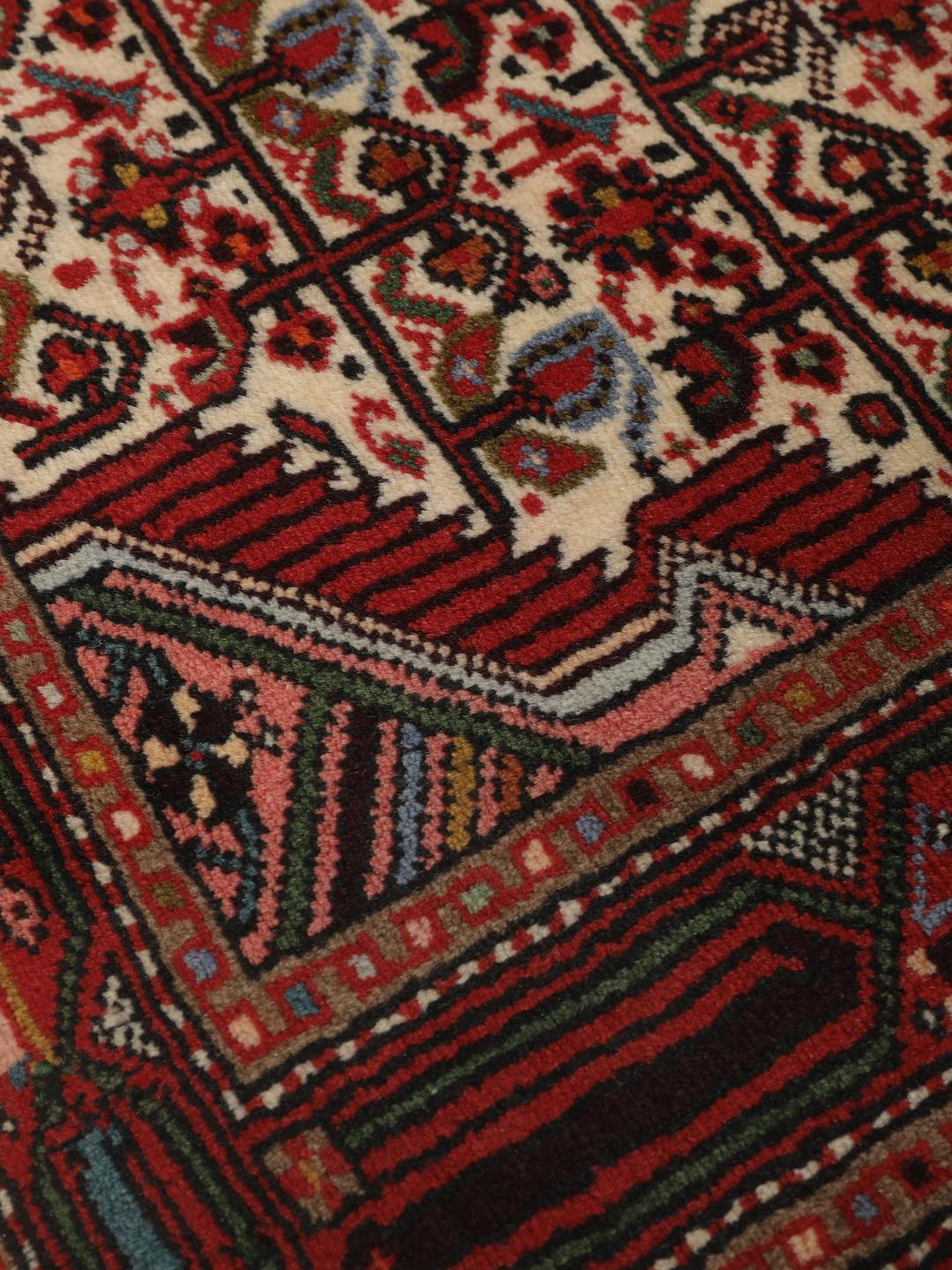 A hand-knotted Hamadan runner with traditional geometric patterns in red and cream.