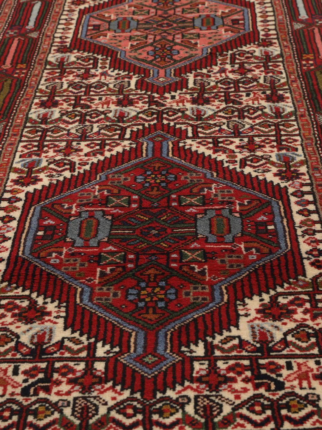 A hand-knotted Hamadan runner with traditional geometric patterns in red and cream.