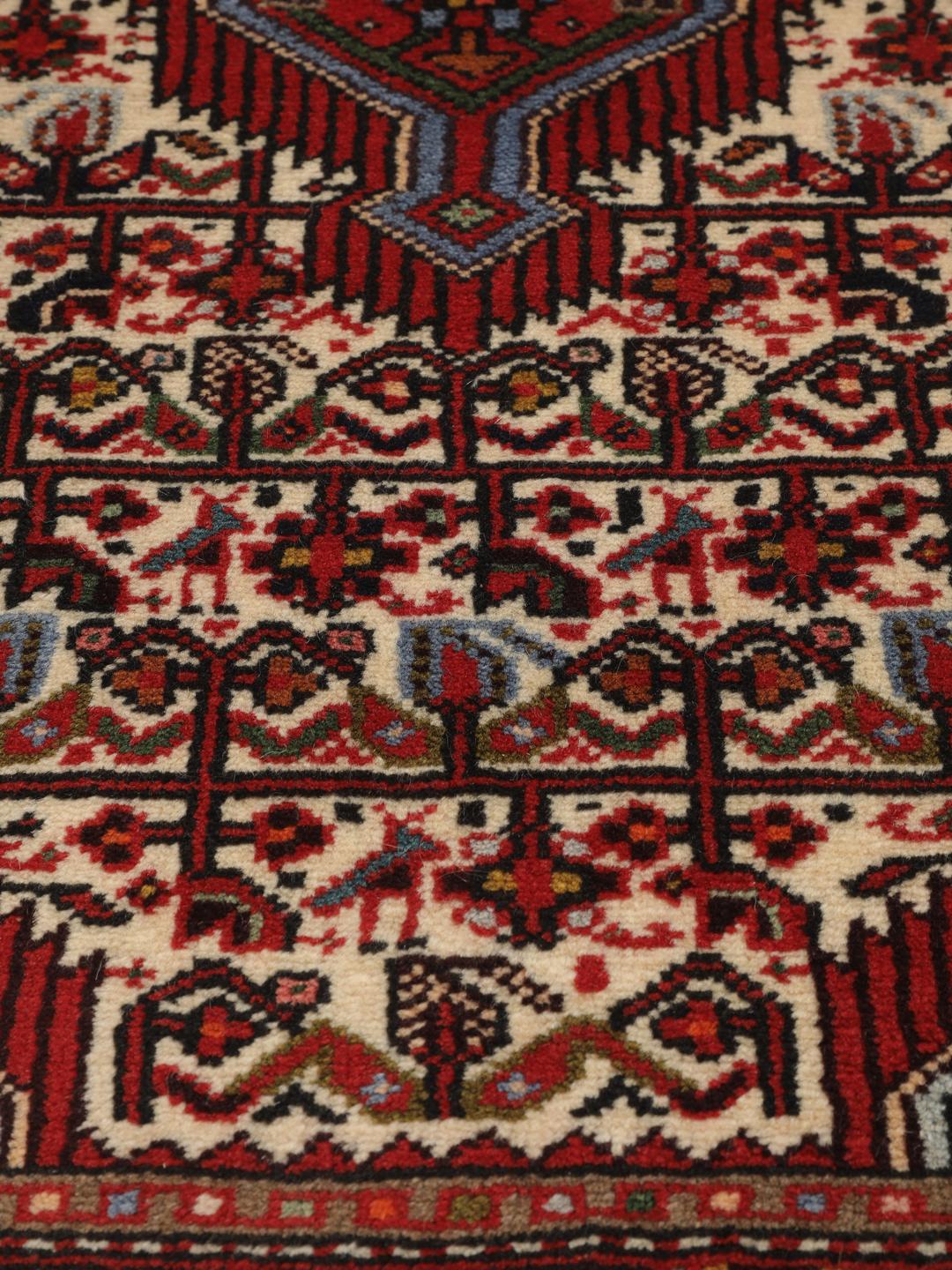 A hand-knotted Hamadan runner with traditional geometric patterns in red and cream.