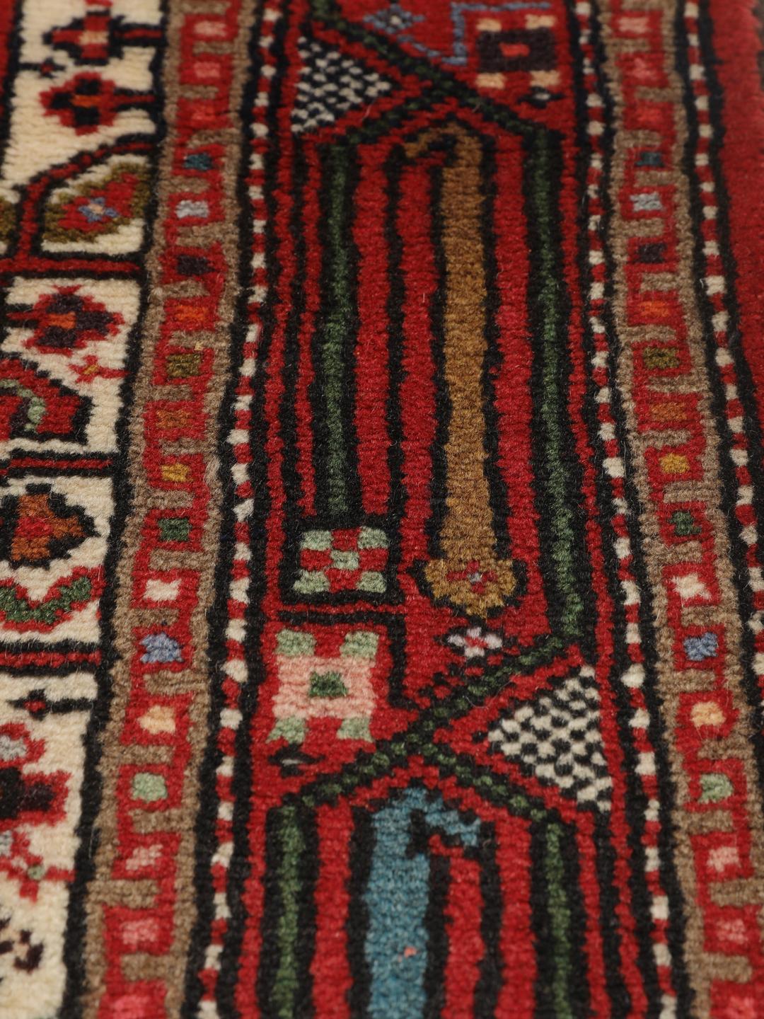 A hand-knotted Hamadan runner with traditional geometric patterns in red and cream.