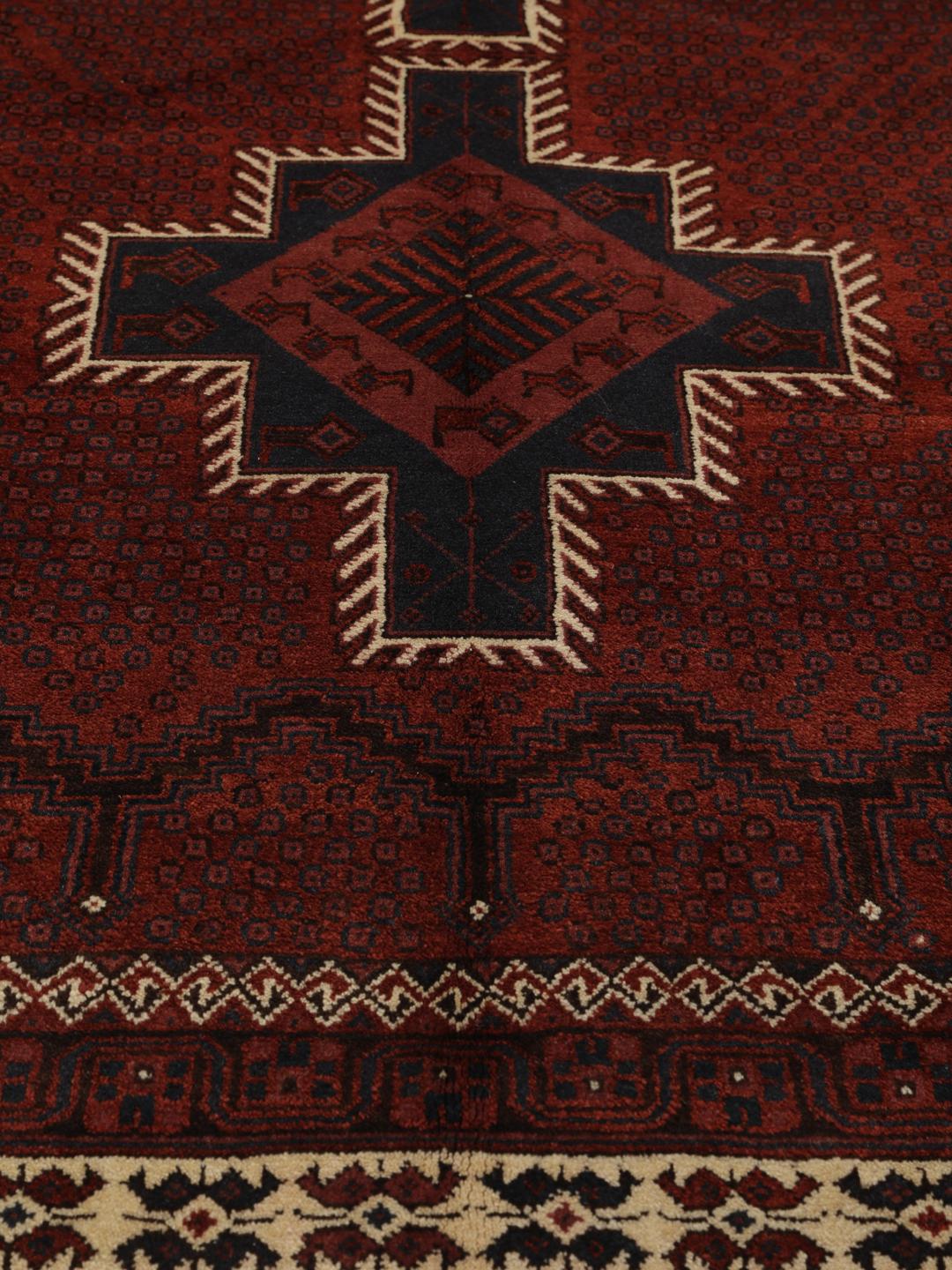 A hand-knotted Afshar rug from the Middle East in deep red featuring geometric medallions.