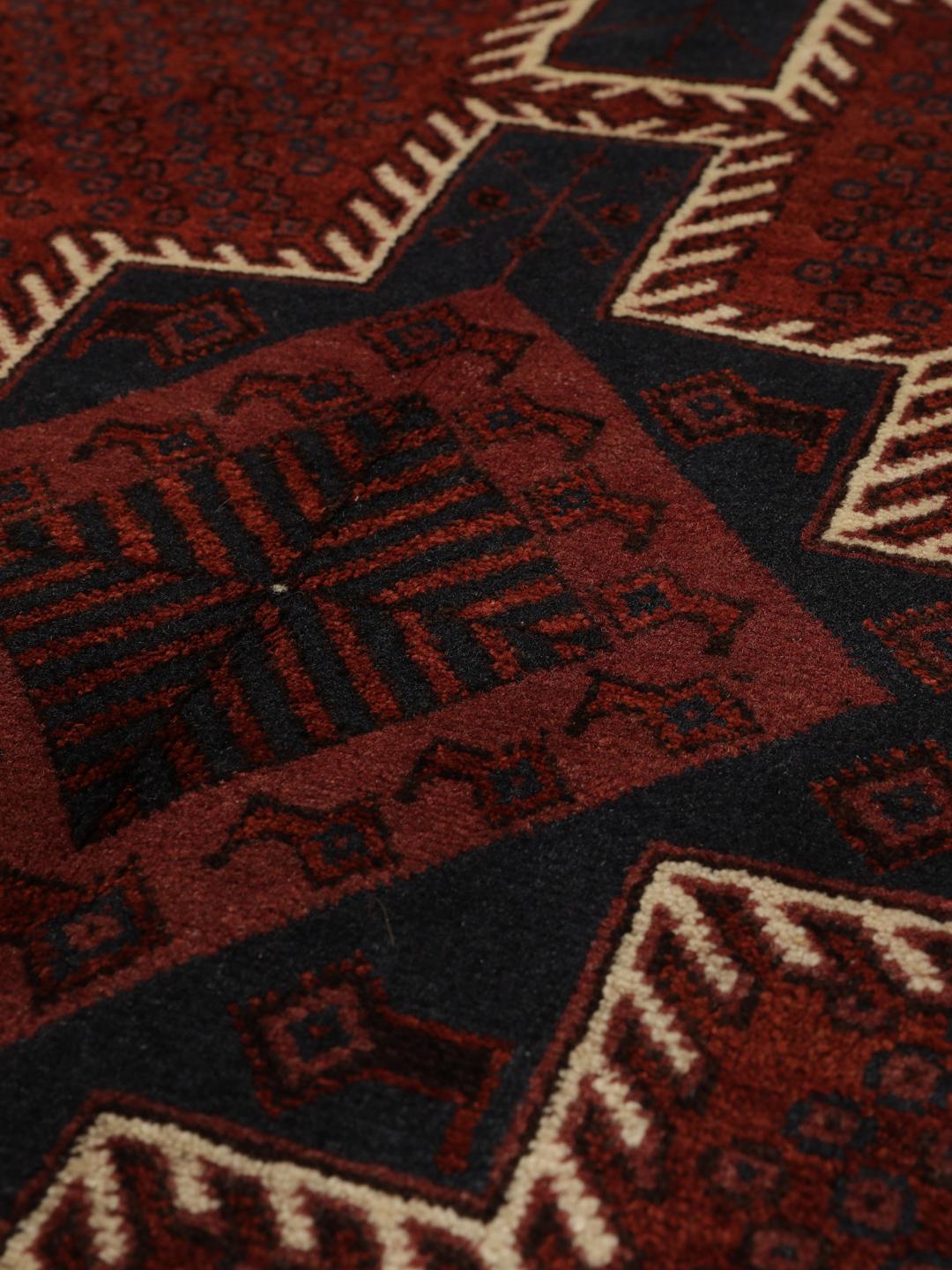 A hand-knotted Afshar rug from the Middle East in deep red featuring geometric medallions.