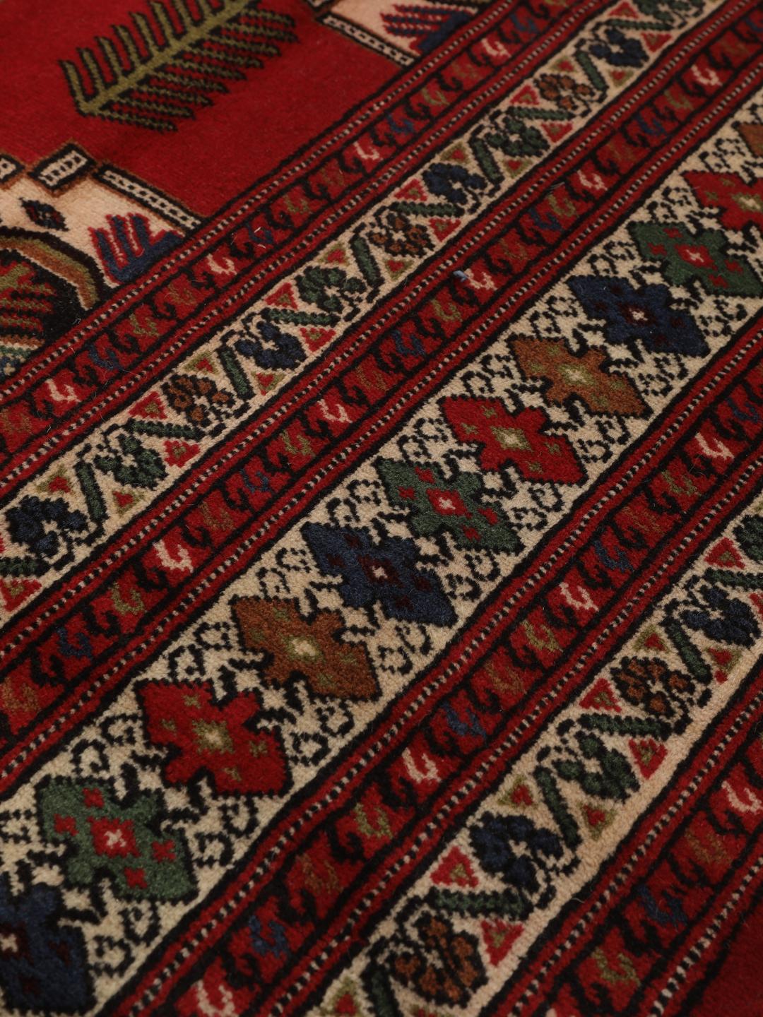 A hand-knotted Turkaman rug from the Middle East with a deep red field and traditional geometric motifs.