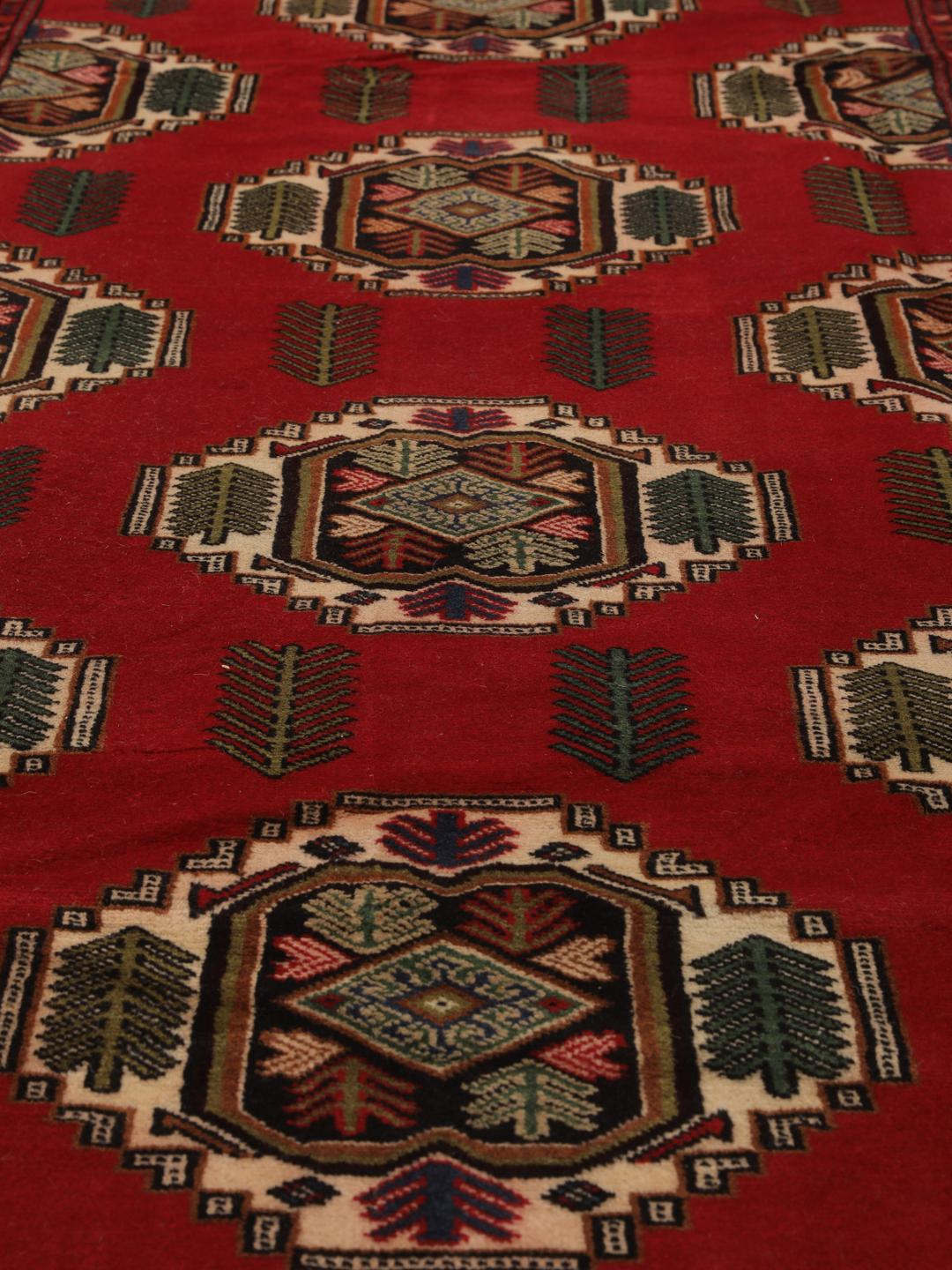 A hand-knotted Turkaman rug from the Middle East with a deep red field and traditional geometric motifs.