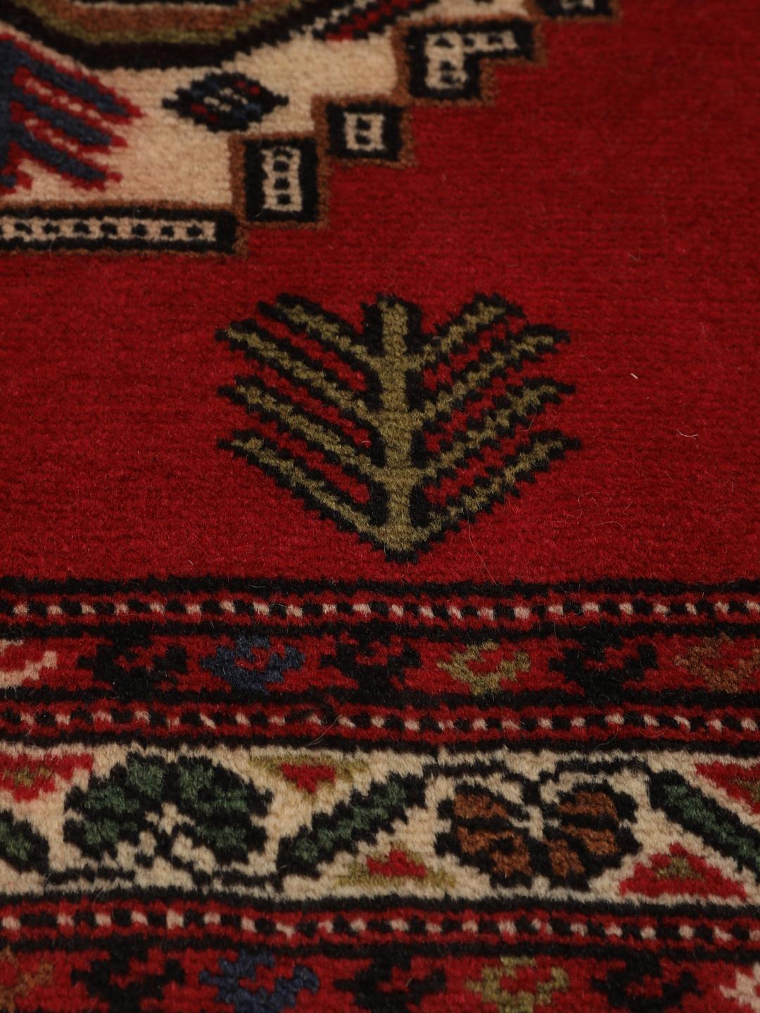 A hand-knotted Turkaman rug from the Middle East with a deep red field and traditional geometric motifs.
