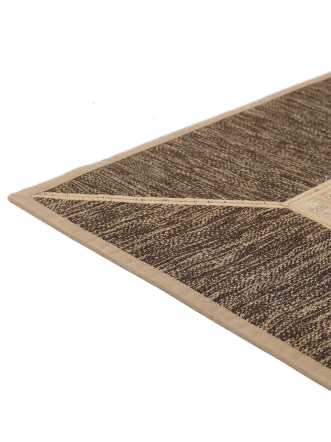 Un tapis patchwork rectangulaire avec des motifs géométriques en beige et marron, tissé à la main au Moyen-Orient.